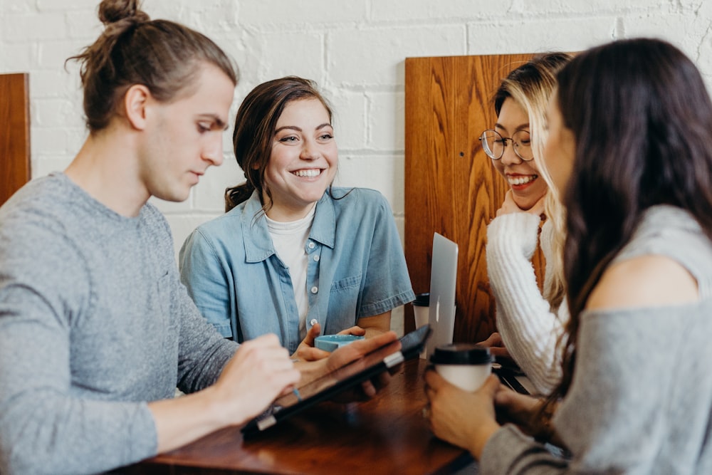 Four people talking and smiling together around a table over coffee